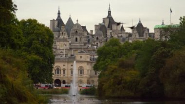 Londra'daki At Muhafızları binalarının sabit bir fotoğrafı Saint James Park'tan çekildi. Bazı arabalar sokağa park edilmiş. Parkta çeşmeli ağaçlar ve rıhtım görülebilir.