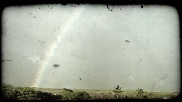 更近的波涛拍击沿海岸线附近阳光岛镇与明亮的彩虹 在山与云背景下的城镇后面下来的镜头 复古风格化视频剪辑 — 图库视频影像