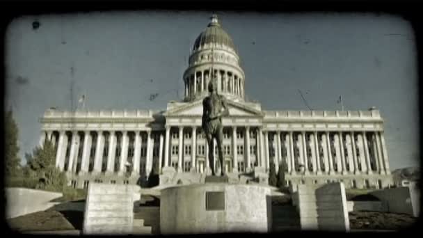 广角镜头的犹他州议会大厦从支柱与楼梯通往其大的大门前面 标志杆的旗帜随风飘扬的风和敬业铜像的尤特印第安人战士纪念碑 — 图库视频影像