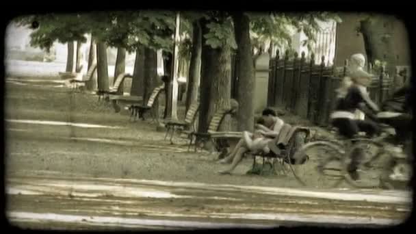 两人在公园的长椅上放松 而别人骑自行车路过 复古风格化视频剪辑 — 图库视频影像