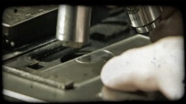 Yeşil sıvı damla ile plastik muayene plaka üzerinde mikroskop ve lensler farklı boyutları arasında hareket altında konumlandırma el kapatın. Vintage stilize video klip.