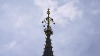 Londra'daki Big Ben saat kulesinin tepesinin aşırı yakın çekim. Sadece sivri üst kısmı görülebilir. Mavi gökyüzü ve bazı bulutlar ile çevrili.