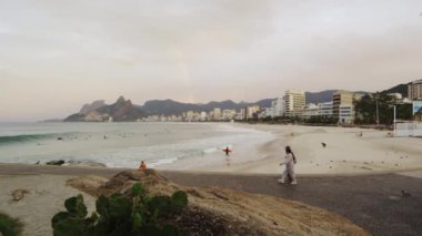 Uzun atış, Ipanema plaj hafif tava, Rio de Janeiro, Brezilya. Bir çift ön planda kum üzerinde yürüyor.