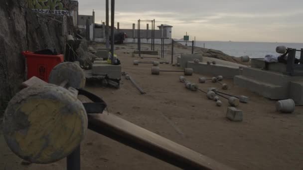 这是静态密切了一些水泥健身器材在里约热内卢伊帕内玛海滩发现 一个人是远的背景下举重 — 图库视频影像