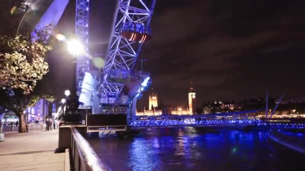 ビッグベンと背景に議会の家と夜のロンドンアイ観覧車のタイムラプスを追跡 — ストック動画