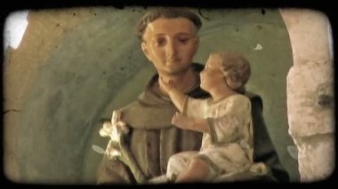 Bir bebek tutan bir keşiş dini bir heykelinin bir yakın çekim. Vintage stilize video klip.