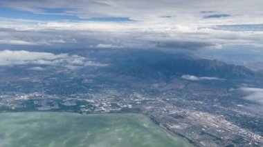 View from airplane flying over Utah Lake as clouds move by looking down into Utah Valley.