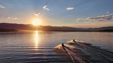 Two people riding towards the sunset on personal watercrafts on Hebgen Lake.