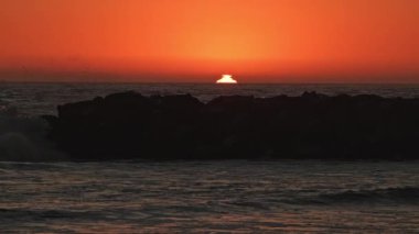 Newport Sahili 'nden güneş ufukta batarken dalgalar süzülüyor..