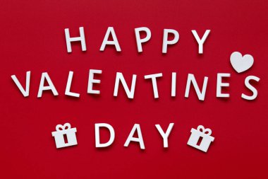 Sevgililer Günü! Beyaz harfler, kalp ve kırmızı arkaplanda iki hediye.