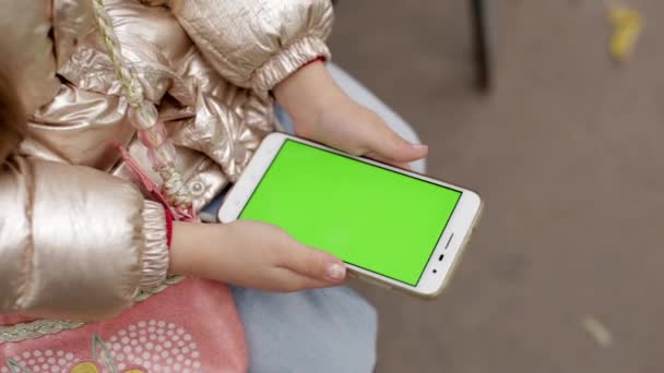 Little girl holding smartphone with green screen. — Stock Video