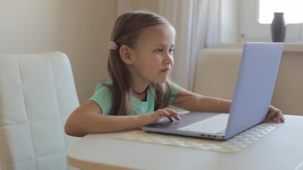 Маленькая симпатичная девочка использует ноутбук для видеозвонков, обучения или игр. — стоковое видео