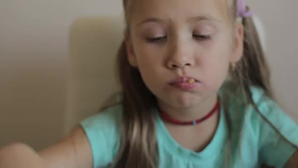 Gadis kecil duduk di meja dan makan kentang goreng dengan saus. Gadis yang mengenakan kaos biru — Stok Video