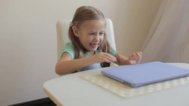 Little cute girl opens laptop to have video call, education or play games.