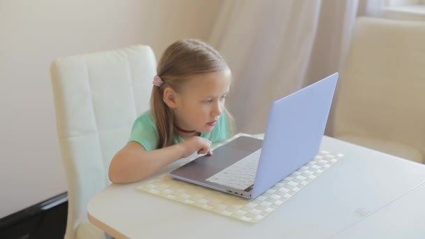 Pequena menina bonito usar laptop para ter chamada de vídeo, educação ou jogar jogos. — Vídeo de Stock