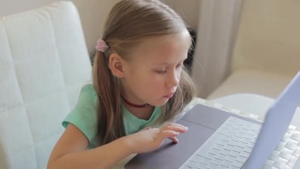 Pequena menina bonito usar laptop para ter chamada de vídeo, educação ou jogar jogos. — Vídeo de Stock