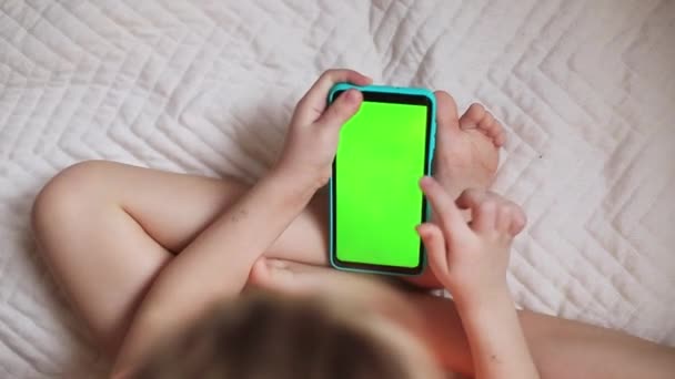 녹색 화면으로 핸드폰을 들고 있는 소녀. 소녀는 게임을 하고 있고 배우는 거리가 멀다. — 비디오