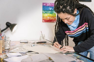 Latin asıllı, genç, güzel, Latin bir sanat yönetmeni. Günlük kıyafetleri ve rastaları olan bir kız. Çalışma masasında, atölyesindeki bir lambayla aydınlatılmış, sinematik bir model tasarlıyor.