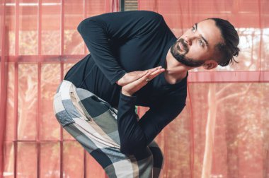 Avuç içleriyle yoga yapan genç bir adamın yan görünüşü ve vücudunun bir yana eğilip eve baktığı görüntüsü..