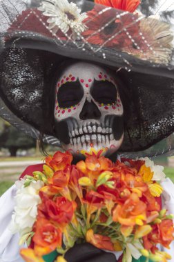 La Calavera Catrina makyajı yapmış, elinde bir buket çiçek tutan yetişkin bir kadının dikey görüntüsü..