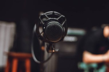 Kayıt sırasında müzik stüdyosundaki siyah yoğunlaştırıcı mikrofonun ön görüntüsü. Prova odasının arka planı bulanık. müzik endüstrisi konsepti.