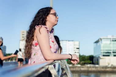 Güzel beyaz kız, bukleli, beyaz, rıhtımda duruyor, tırabzana yaslanıyor, dalgın dalgın denize bakıyor, teknenin dünya turuna çıkmasını bekliyor. Turizm kavramı.