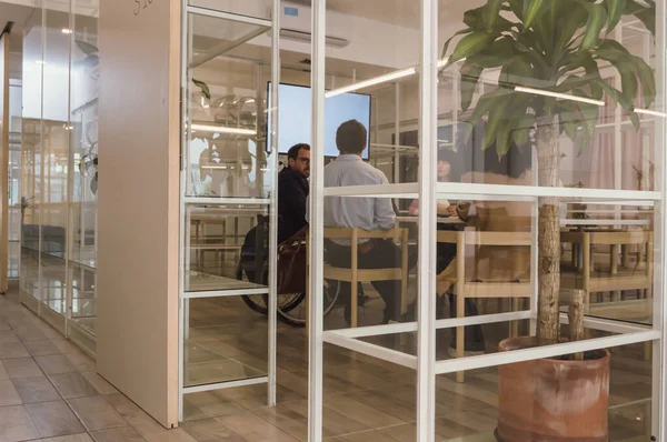 Side view of mixed group of Latino Hispanic staff gathered in a green ecological office in a coworking space, talking about financed business and digital asset trading.