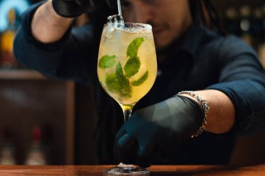 Uzman bir barmen, bir mikserle, içkisini rom, portakal suyu ve naneyle bitiriyor, bir gece kulübünde, bar konseptinde..