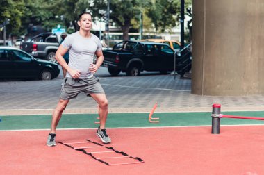 Genç atletik adam dışarıda egzersiz yapıyor, hareketsiz koşuyor, antrenman meydanında, gri giyinmiş, fitness konsepti..