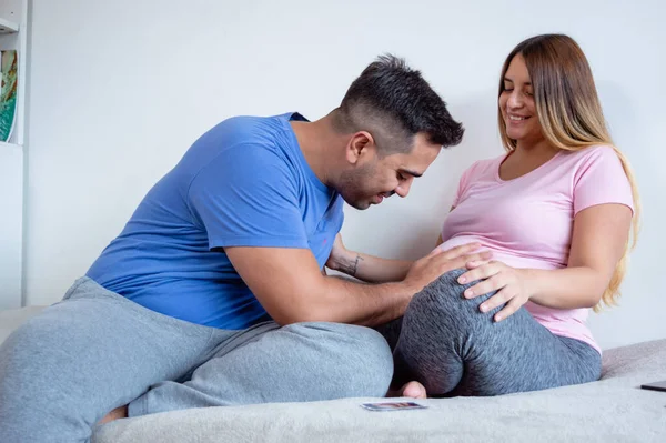 寝室のベッドの上に横になっている白人男性妊娠中の腹の妻を見て感動させ笑顔で共に楽しみライフスタイルの概念 — ストック写真