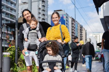 Sokakta güzel beyaz bir ailenin portresi. Komik yüzlü bir adama ve kızlarıyla birlikte şehre yürüyen bir kadına bakıyorlar..