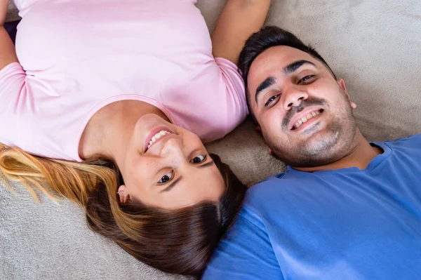 異性愛の白人ベネズエラ人のカップルがベッドの上に横になってカメラを見て笑っていました — ストック写真