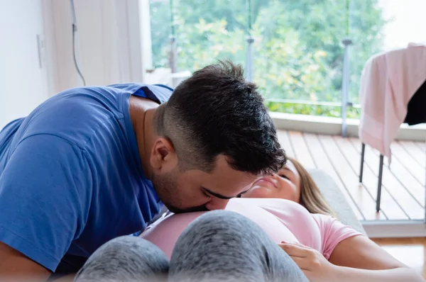 Kafkasyalı mutlu adam hamile karısını öpüyor balkon manzaralı yatakta uzanıyor, boşluğu kopyalıyor.