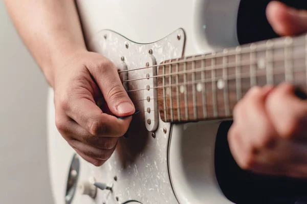 Tanımlanamayan beyaz adam plectrum ile elektro gitar çalıyor, sağ ele odaklan, boşluğu kopyala.