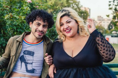 Bukleli genç bir adamın portresi ve güzel, genç, iri yarı bir kadın, beyaz arkadaşları, parkta oturuyor, günbatımının tadını çıkarıyor..