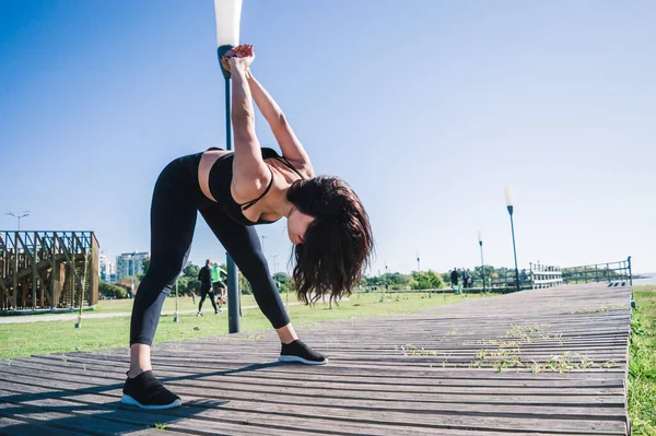 年轻的高加索拉丁女子 在海滨公园的木制人行道上 伸展肌肉开始训练 模仿空中的空间 — 图库照片