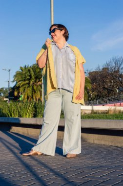 Güzel modaya uygun genç beyaz kadın dışarıda poz veriyor, günlük kıyafetler giyiyor güneş gözlüğü, kısa saç ve güneş gözlüğü takıyor. dikey resim.