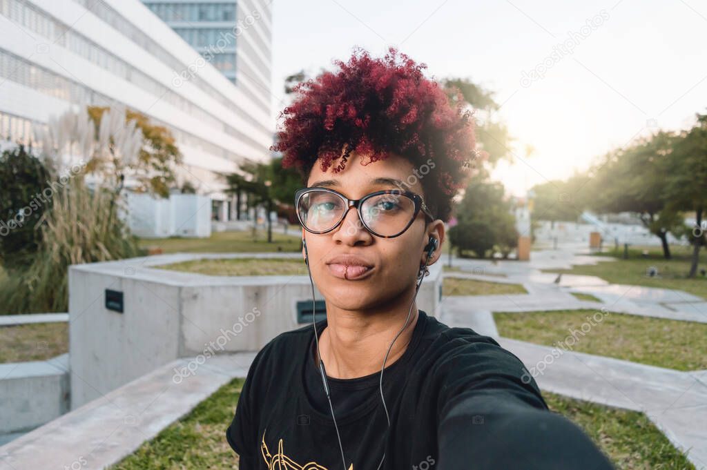 close up portrait, young latin colombian woman with afro and glasses, serious annoyed taking a selfie, front view and phone perspective
