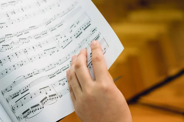 young caucasian female hand turning the page of sheet music, first person perspective with copy space.