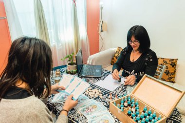 Muayenehanesinde, evinde, kadın hastasına stres ve anksiyete tedavisi için bach çiçeği reçetesi yazan bütünsel tıp kadını..