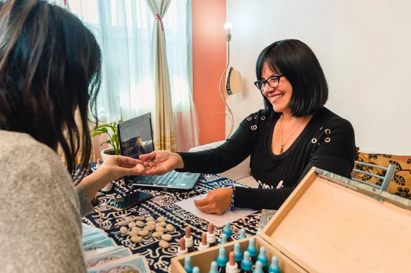 Caucasian Latin adult woman in holistic medical consultation smiling attending a patient, showing her alternative treatments.