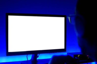 Karanlıkta bilgisayar monitörünü izleyen bir adamın yakın plan görüntüsü, etrafında mavi ışıklar olan, bir ev müziği stüdyosunda, ekrana odaklanmış.