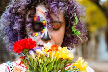Yakından ve önden beyaz kadın portresi La Calavera catrina makyajlı gözleri kapalı ve açık havada çiçek kokan
