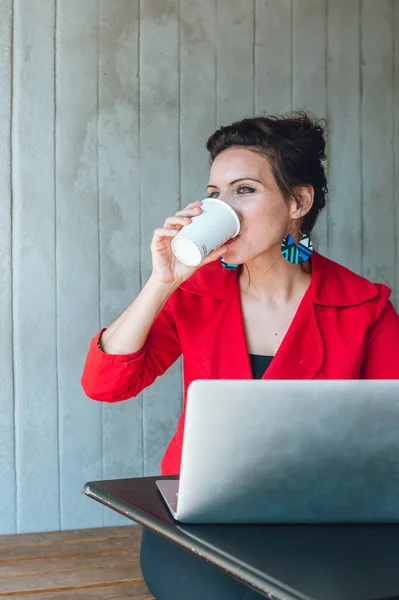 vertical image business woman drinking coffee while working with her laptop, business and social media concept.