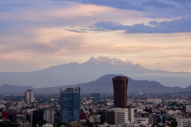 Mexico City 'nin panoramik fotoğrafı, arka planda Iztlacihuatl volkanları ve popocatepetl manzaralı bulutlu bir öğleden sonra.