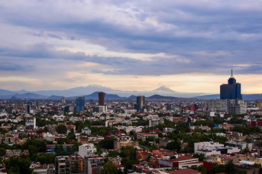 Mexico City 'nin panoramik fotoğrafı, arka planda Iztlacihuatl volkanları ve popocatepetl manzaralı bulutlu bir öğleden sonra.