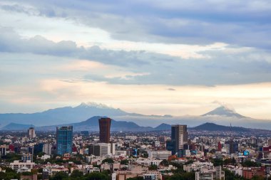 Mexico City 'nin panoramik fotoğrafı, arka planda Iztlacihuatl volkanları ve popocatepetl manzaralı bulutlu bir öğleden sonra.
