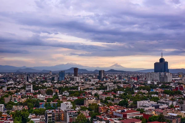 Mexico City 'nin panoramik fotoğrafı, arka planda Iztlacihuatl volkanları ve popocatepetl manzaralı bulutlu bir öğleden sonra.