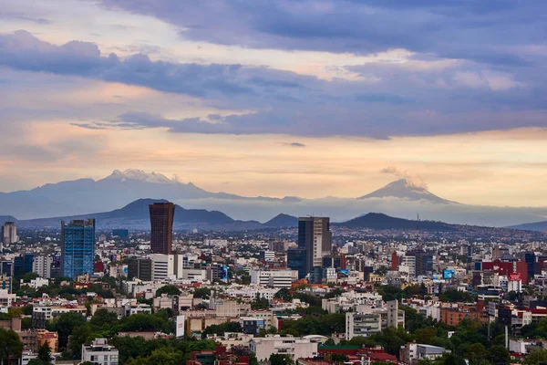 Mexico City 'nin panoramik fotoğrafı, arka planda Iztlacihuatl volkanları ve popocatepetl manzaralı bulutlu bir öğleden sonra.