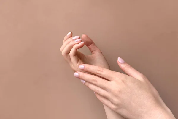 Güzel kadınların elleri bej arka planda losyon ya da krem sürerken. Doğal pembe manikürlü avuç içleri. Cilt bakımı. Yumuşak, temiz el kavramı.